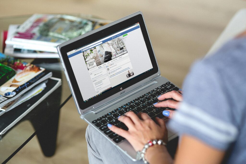 hands-woman-laptop-notebook-6168 A woman typing on a laptop with social media on the screen, indoors setting.